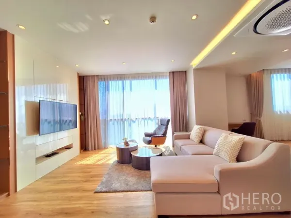 อพาร์ทเมนท์ ให้เช่าในBang Na, Bangkok - ห้องนั่งเล่นสว่างด้วยหน้าต่างเต็มผนัง โซฟา L‑shape และผนังทีวี