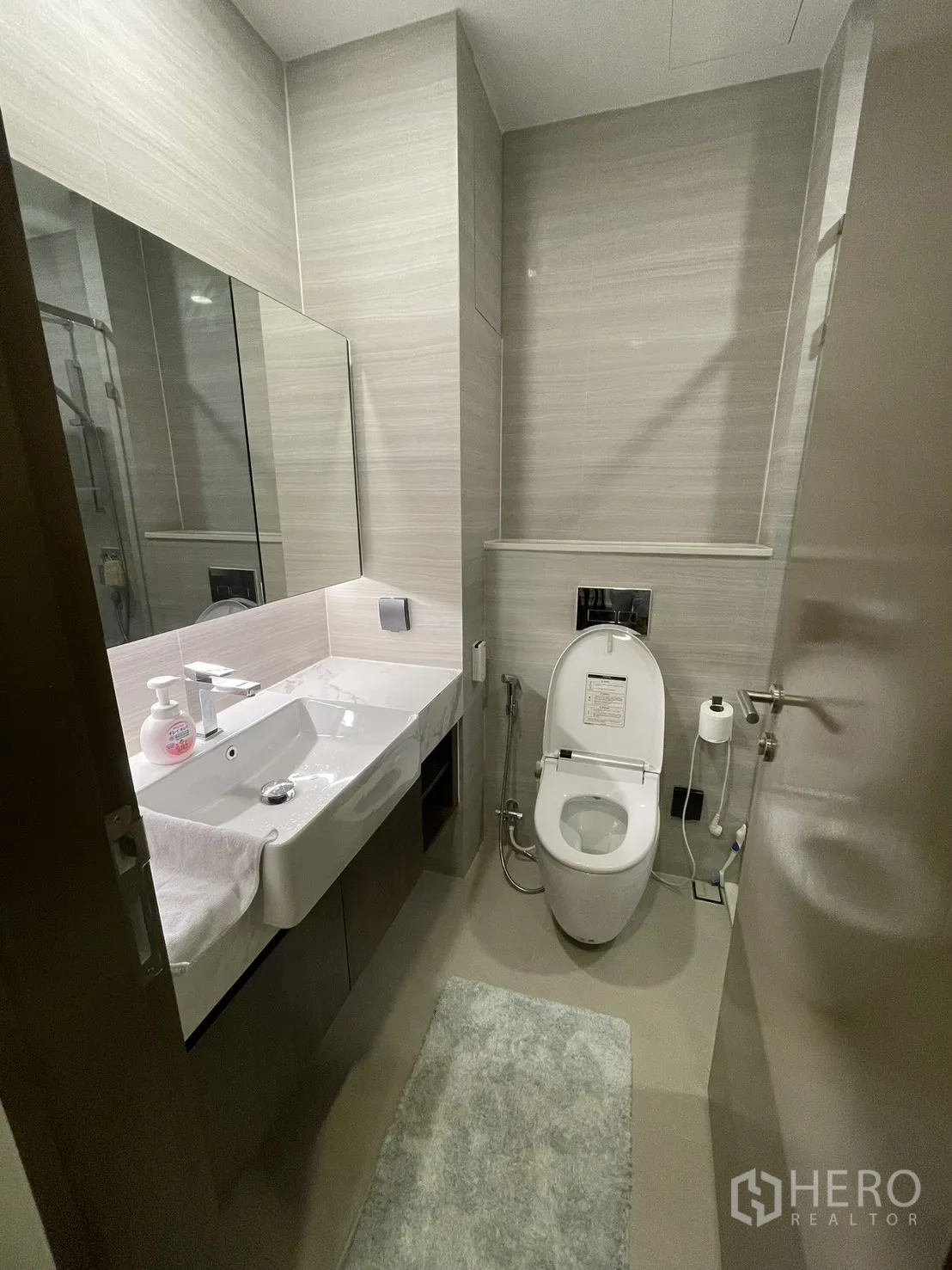 Condominium for rent in Watthana, Bangkok - Bathroom vanity with large mirror, countertop sink, and toilet.