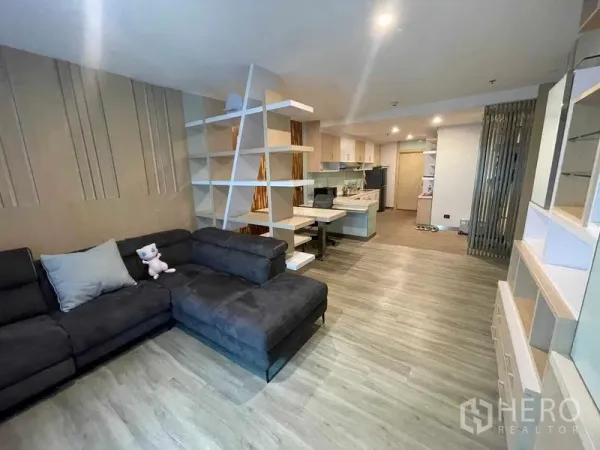 Condominium for rent in Sathon, Bangkok - Another angle of the open living area showing sectional sofa, shelving divider and extensive built-in storage.
