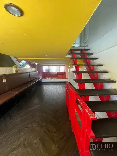 อาคารพาณิชย์ ให้เช่าในKhlong Toei, Bangkok - ชั้นลอยพร้อมบันไดและราวสีแดง มีเบาะที่นั่งบิวท์อิน ใต้เพดานสีเหลือง