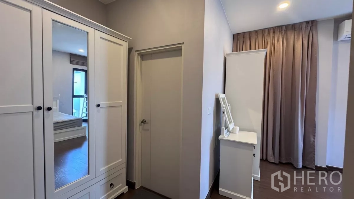 บ้าน ให้เช่าหรือขายในSaphan Sung, Bangkok - มุมแต่งตัวเห็นตู้เสื้อผ้าสีขาวและประตูห้องน้ำ โทนสีเรียบสบายตา.