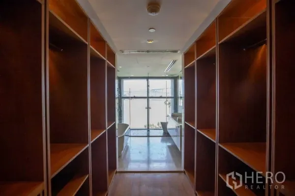 公寓 出租在Yan Nawa, Bangkok - 步入式衣帽间走廊，内置木质柜体，尽头通向带浴缸的明亮卫浴