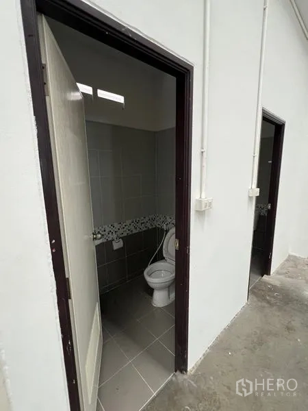 货栈 出租在Phra Samut Chedi, Samut Prakan - 仓库卫生间入口，瓷砖地面与白色门框。