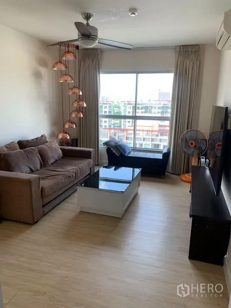 คอนโด ให้เช่าในBang Na, Bangkok - ห้องนั่งเล่นอบอุ่น โซฟา พัดลมเพดาน ชุดวางทีวี โต๊ะกลาง และหน้าต่างเต็มบานมองเห็นชุมชน