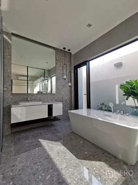 Detached House for sale in Saphan Sung, Bangkok - Spa-style bathroom with a freestanding bathtub, large mirror and natural light.