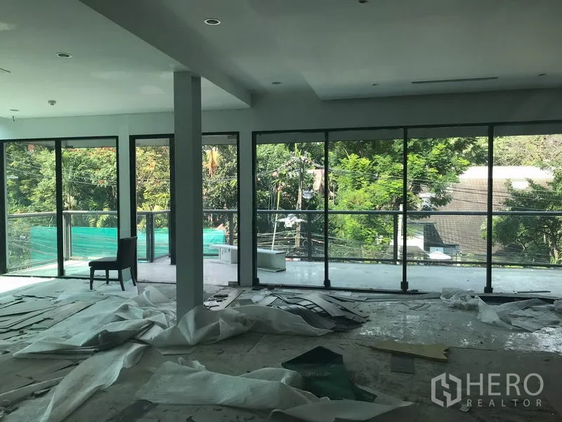 零售空间 出租在Watthana, Bangkok - 明亮销售区，环绕玻璃与阳台，眺望绿意景观。