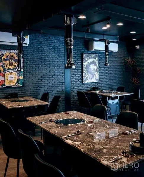 独立式住宅 出租在Watthana, Bangkok - 宽敞餐厅，多张石材桌、黑色座椅与外露通风管道。