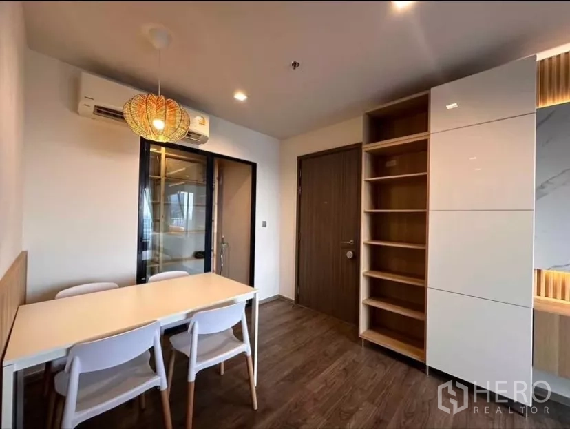 Condominium for rent in Chatuchak, Bangkok - Dining nook with four-seat table, pendant light, and built-in shelving by the entry.