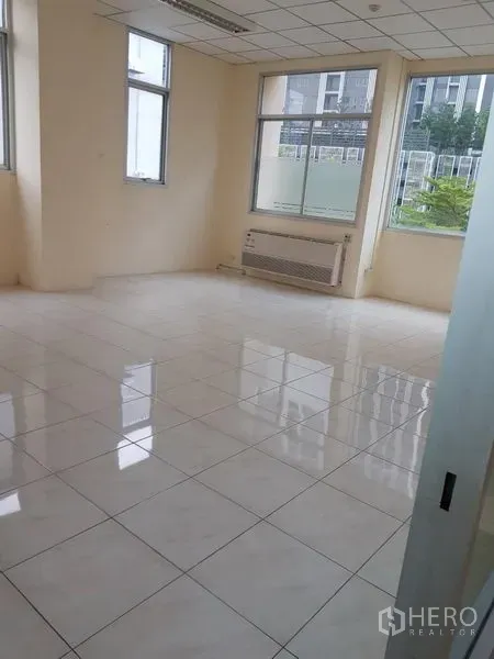 办公空间 出租在Phra Khanong, Bangkok - 开放式办公区，自然采光充足，壁挂空调、白色瓷砖地面，窗外绿景。