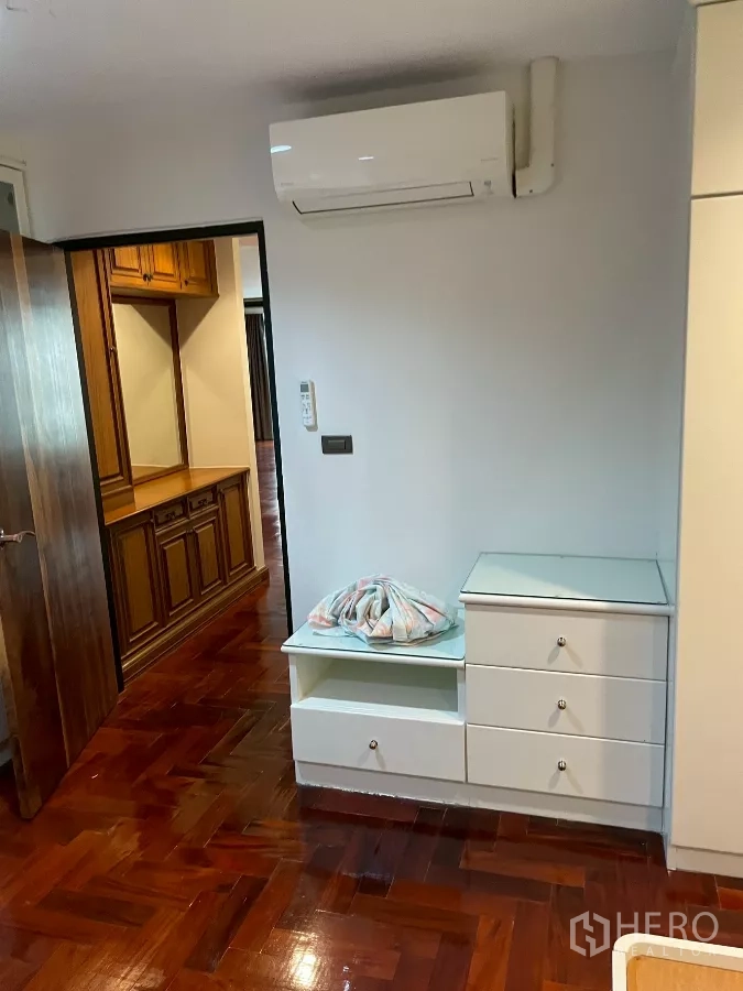 คอนโด ขายในWatthana, Bangkok - มุมห้องนอนมีเครื่องปรับอากาศ ตู้ลิ้นชักสีขาว และทางเดินไปยังโถง