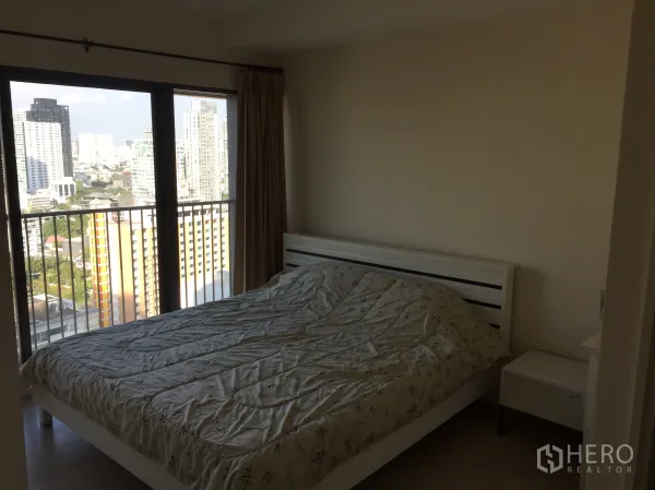 公寓 出租或出售在Khlong Toei, Bangkok - 卧室配大窗与阳台栏杆，可见曼谷天际线与双人床。