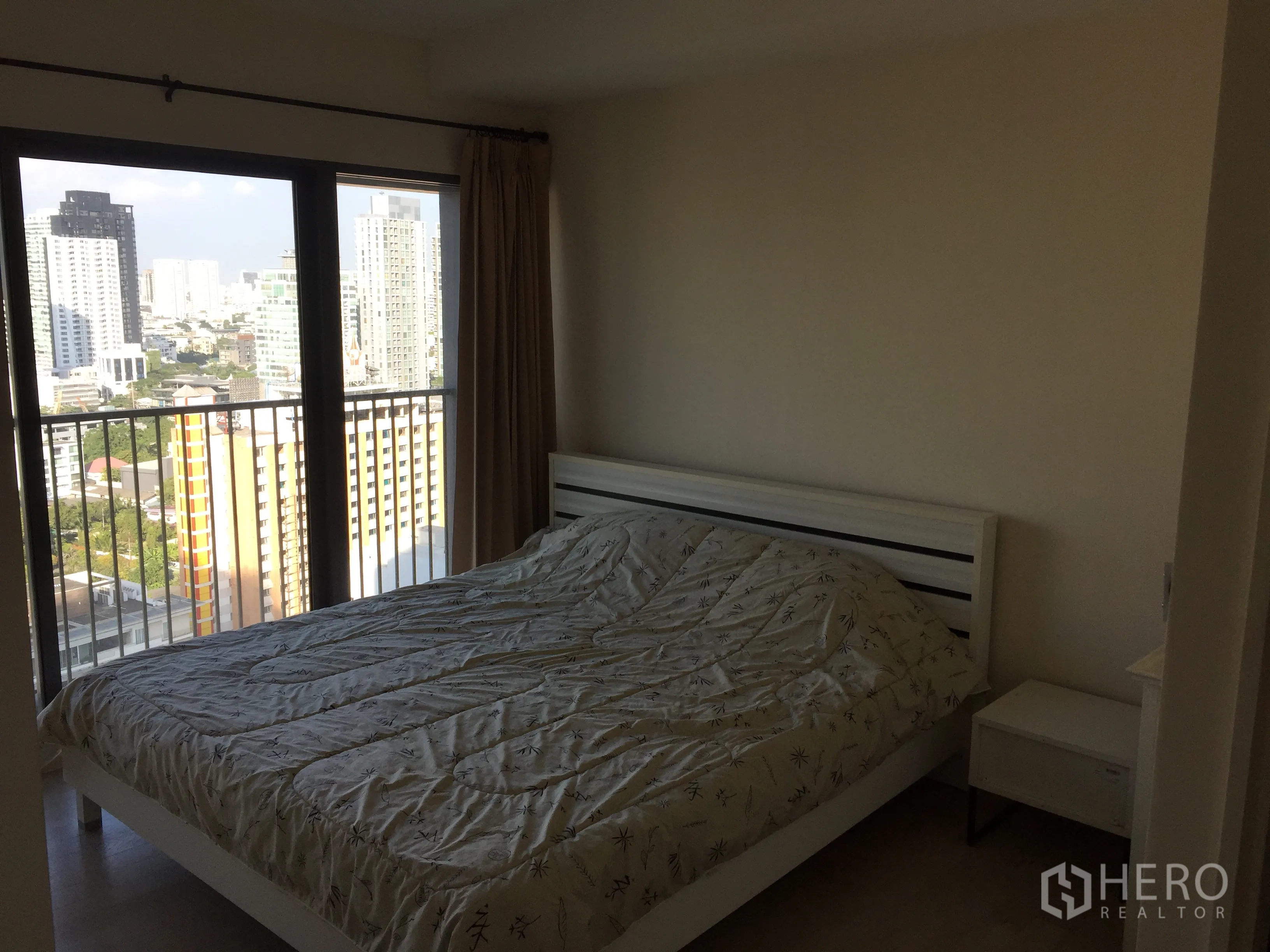 公寓 出租或出售在Khlong Toei, Bangkok - 卧室配大窗与阳台栏杆，可见曼谷天际线与双人床。