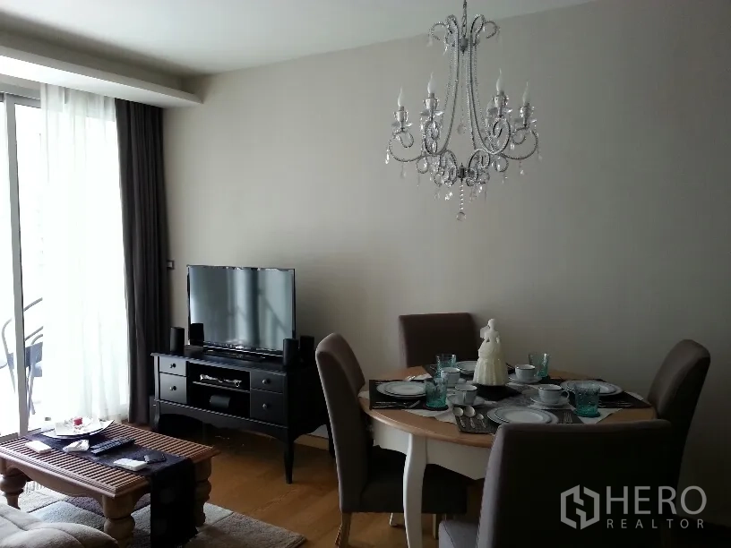 คอนโด ให้เช่าในWatthana, Bangkok - โซนรับแขกและทานอาหารแบบเปิด โล่ง มีโคมระย้า โต๊ะกลม ตู้วางทีวี และประตูกระจกออกไประเบียง