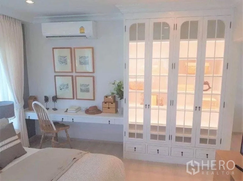 Detached House for rent in Bang Bo, Samut Prakan - Bright bedroom with built-in white wardrobe, long desk and air conditioner.