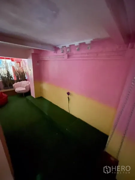 店屋 出租在Ratchathewi, Bangkok - 粉黄配色房间，人工草坪地面与休闲座椅。