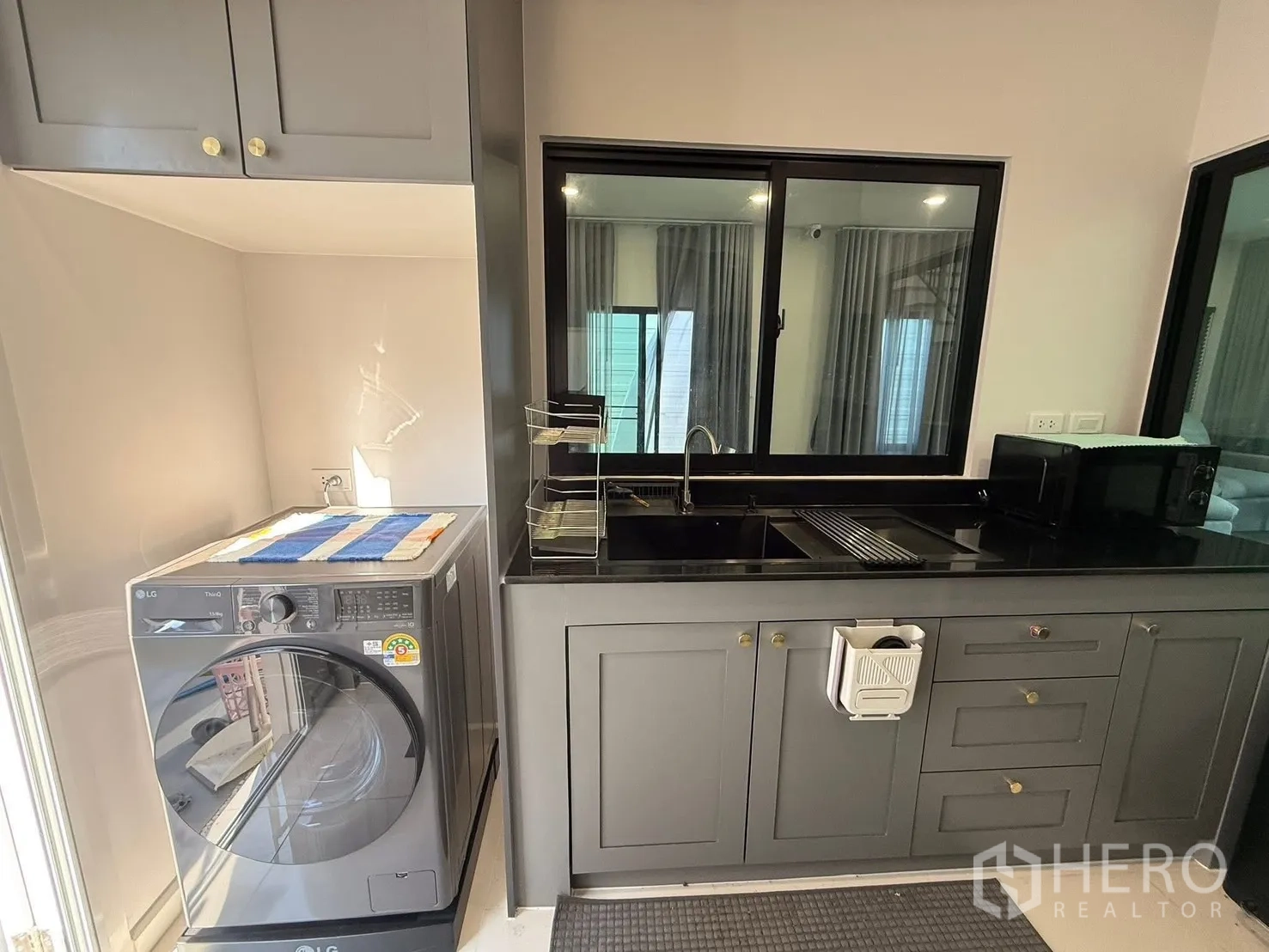 Detached House for rent in Bang Phli, Samut Prakan - Utility and kitchen area with sink, cabinets and a front-load washer.