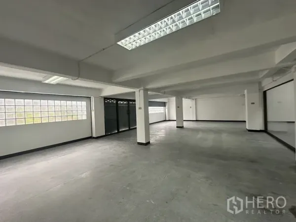 Office Space for rent in Khlong Toei, Bangkok - Open-plan floor with structural columns, strip lights and glass block windows for natural light.