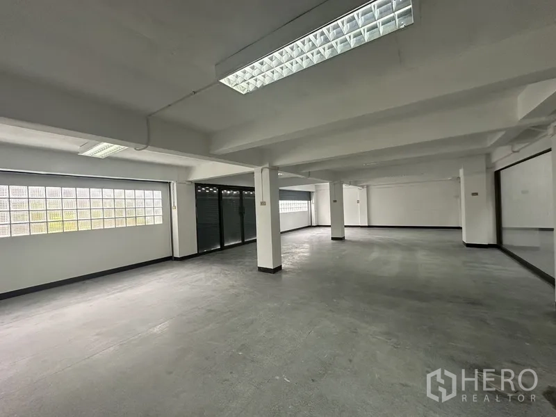 Office Space for rent in Khlong Toei, Bangkok - Open-plan floor with structural columns, strip lights and glass block windows for natural light.