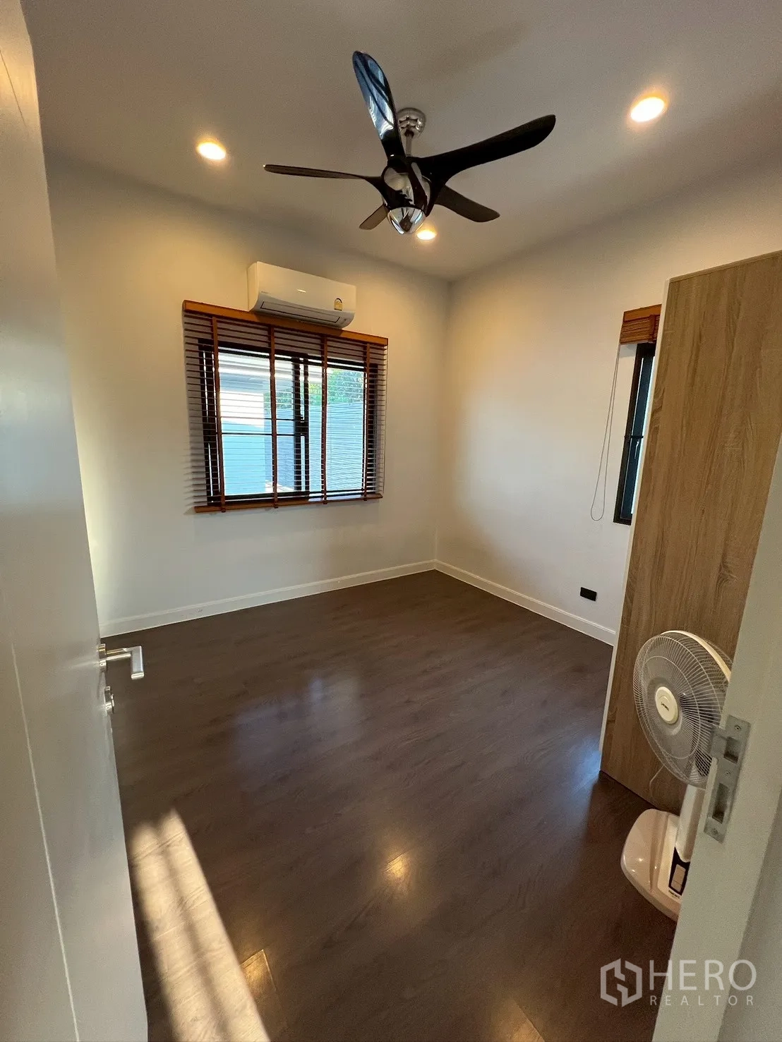 独栋房屋 for rent in Bang Kapi, Bangkok - 温馨卧室，配空调、吊扇和两扇带木百叶的窗户。