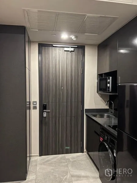 Condominium for rent in Watthana, Bangkok - Entry hallway facing sleek kitchen cabinetry and a wood-grain door.