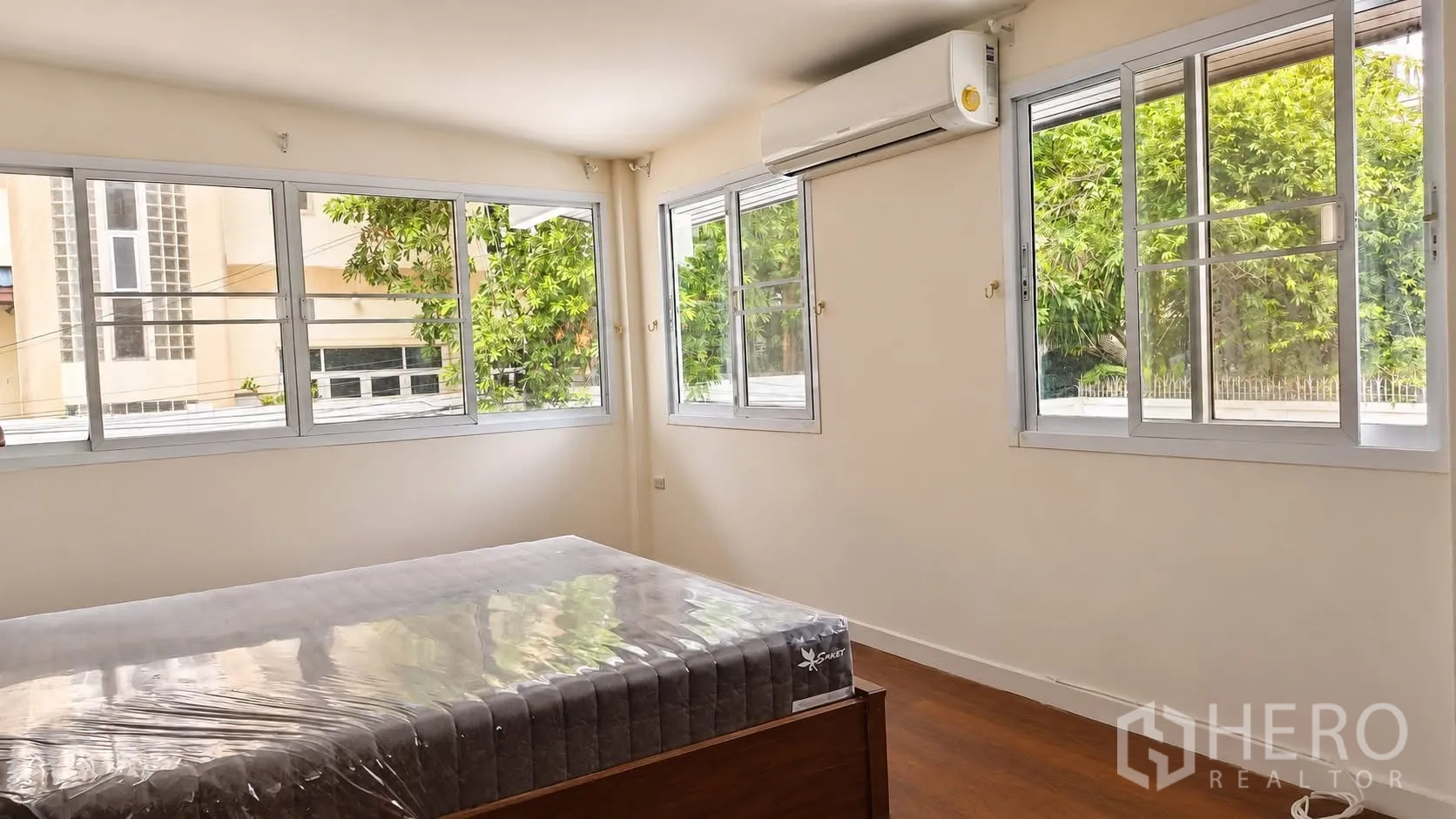 Detached House for rent in Khlong Toei, Bangkok - Corner bedroom with multiple windows, new mattress, and air-conditioning unit.