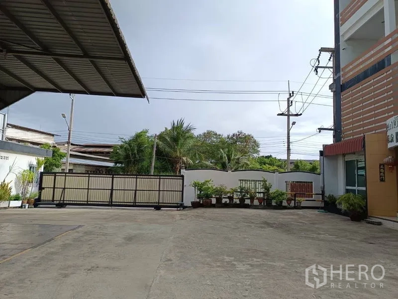 工厂 出售在Ban Phaeo, Samut Sakhon - 滑动大门与宽阔前院，电线杆与绿化可见