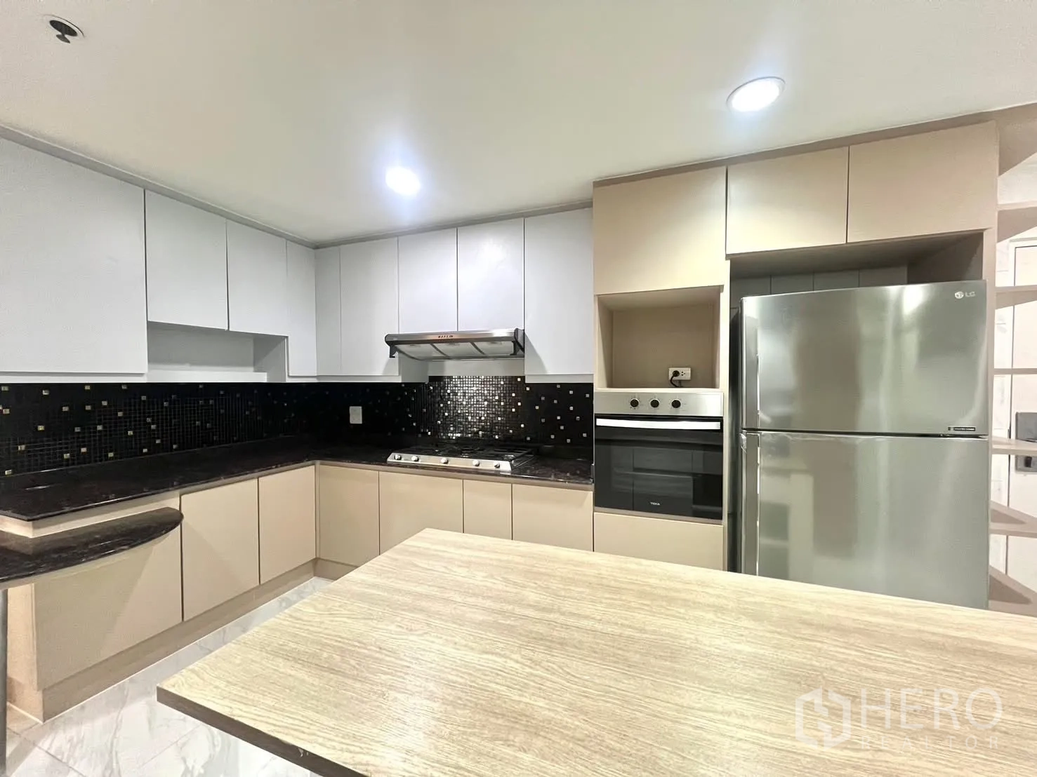 Condominium for rent in Khlong Toei, Bangkok - Kitchen corner with cooktop, hood, oven, fridge and black tile backsplash.