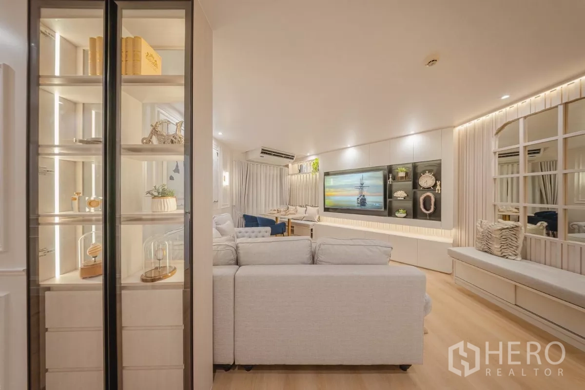 Condominium for rent in Yan Nawa, Bangkok - Entry view to the living area with glass display cabinet, sectional sofa and TV feature wall.