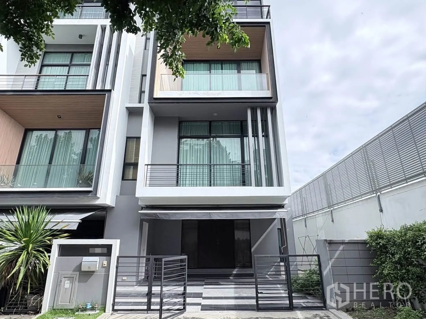 Detached House for rent in Saphan Sung, Bangkok - Contemporary house façade with balconies, large windows, and a gated carport.