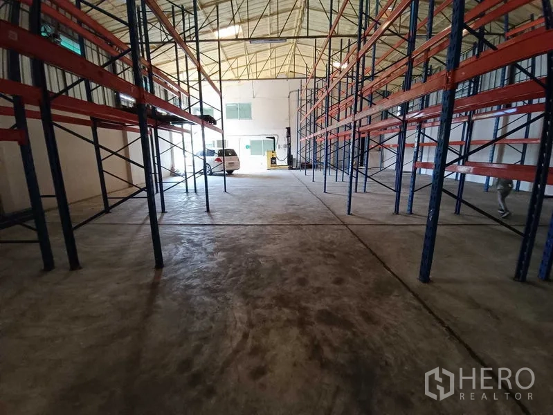 Warehouse for rent in Suan Luang, Bangkok - Central aisle between tall pallet racks leading to the loading entrance.