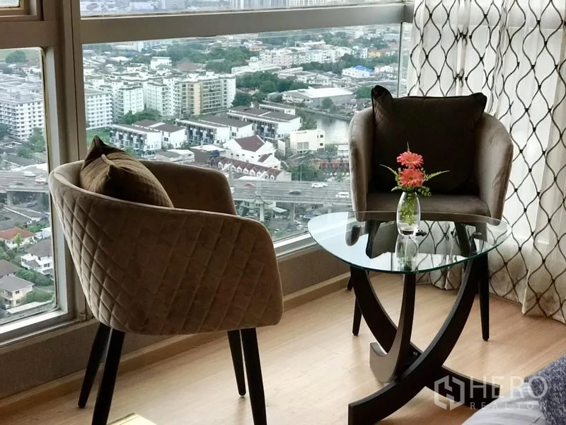 คอนโด ให้เช่าในKhlong Toei, Bangkok - มุมนั่งชมวิวติดหน้าต่าง เก้าอี้สองตัวกับโต๊ะกระจกทรงกลม มองเห็นวิวเมือง.