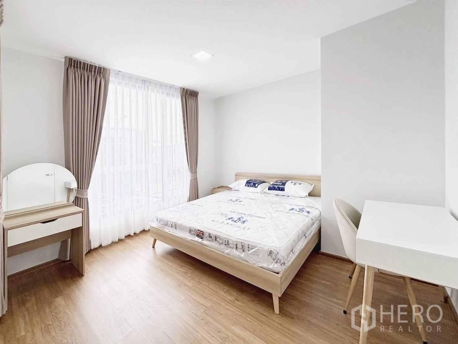 ทาวน์เฮาส์ for rent in Bang Phli, Samut Prakan - ห้องนอนใหญ่มีเตียง โต๊ะเครื่องแป้ง โต๊ะทำงาน และหน้าต่างสูงพร้อมผ้าม่าน.