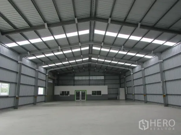 Warehouse for rent in Pak Kret, Nonthaburi - Spacious warehouse interior with high gabled roof, skylights and an internal office block.