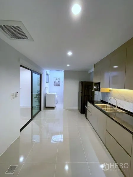 Townhouse for rent in Bang Phli, Samut Prakan - Sleek kitchen with long countertops, glossy cabinets and refrigerator.