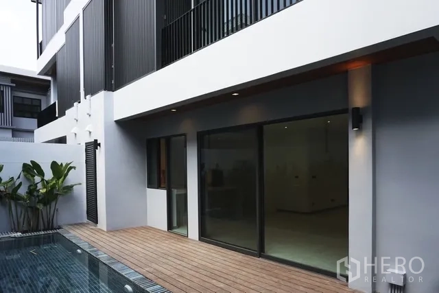Detached House for rent in Watthana, Bangkok - Poolside wooden deck with sliding glass doors opening to the interior.