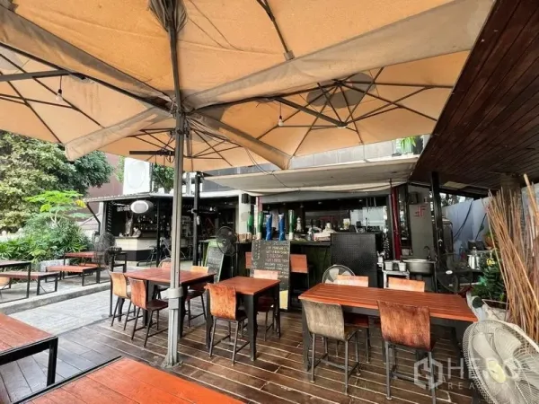 零售空间 出租在Watthana, Bangkok - 遮阳伞下的露天座位，配风扇，后方可见吧台区域。