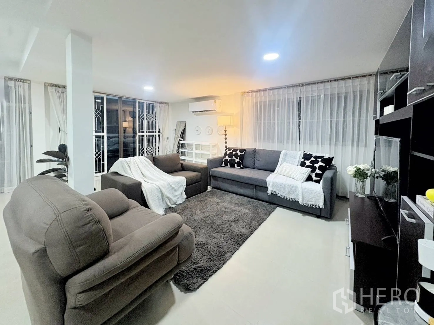 บ้านเดี่ยว for rent in Huai Khwang, Bangkok - ห้องนั่งเล่นโปร่ง โซฟาหลายชุด พรม ชั้นวาง และหน้าต่างบานกว้าง