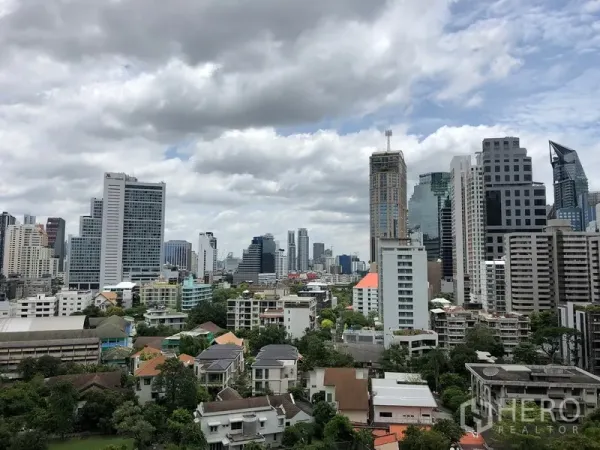 Condominium for sale in Khlong Toei, Bangkok - Bangkok city skyline with high-rise towers and leafy low-rise neighborhood in the foreground.