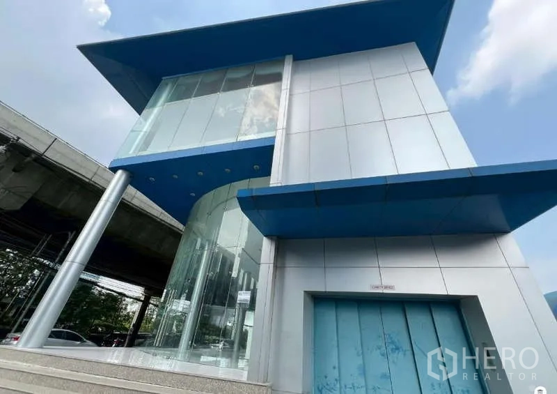 展厅 出租 - 展示厅立面设有弧形玻璃入口与银色金属板、蓝色雨棚。