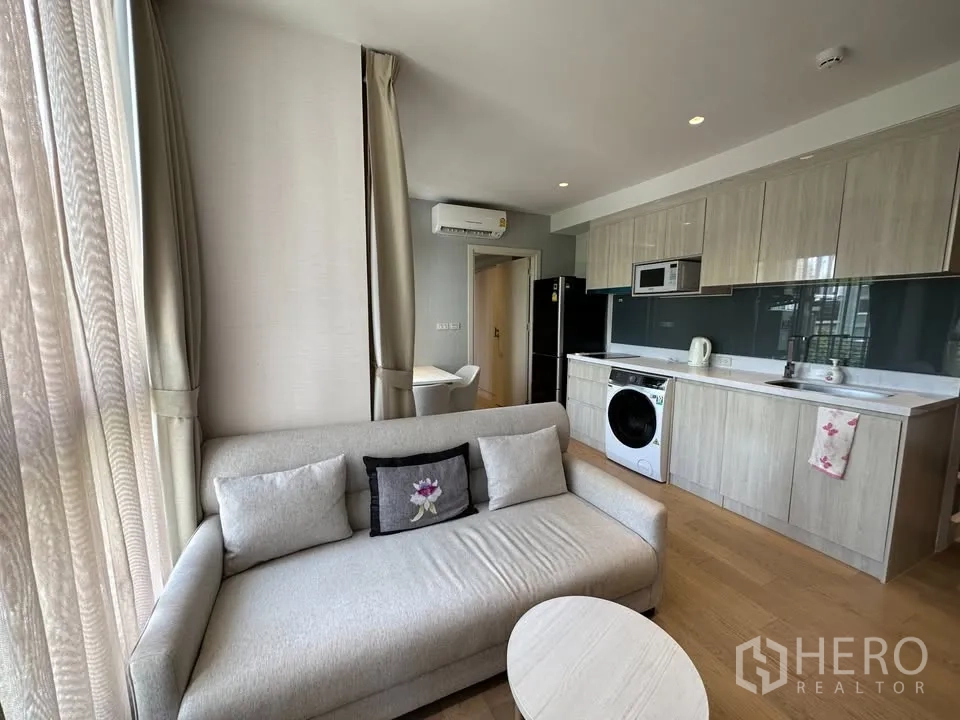 公寓 for rent in Watthana, Bangkok - 开放式客厅配沙发，整墙厨房带橱柜、微波炉、冰箱与洗衣机。
