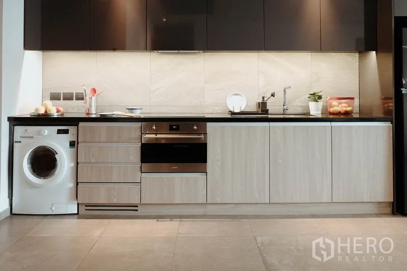Condominium for rent in Watthana, Bangkok - Built-in kitchenette with oven, cooktop, sink, and in-unit washing machine.