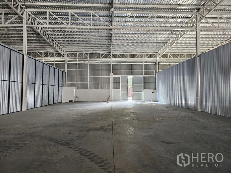 货栈 出租在Khlong Toei, Bangkok - 开放式仓库大厅，层高充裕，金属墙体与后部出入口采光。