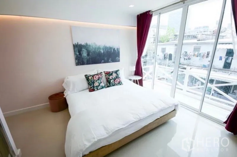 Townhouse for rent in Ratchathewi, Bangkok - Bedroom with large bed, floor-to-ceiling windows and access to a balcony.