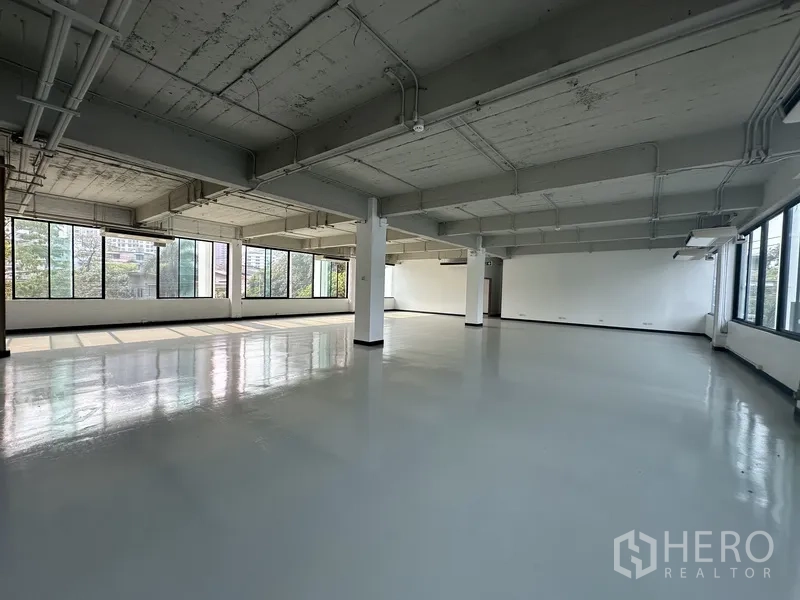 Office Space for rent - Wide open-plan office with epoxy flooring, pillars and windows on two sides.