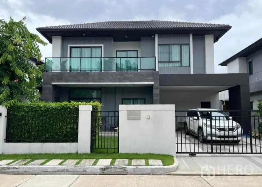 独立式住宅 出售在Khan Na Yao, Bangkok - 房屋正立面图：两层独栋别墅，带安全围栏与车棚。