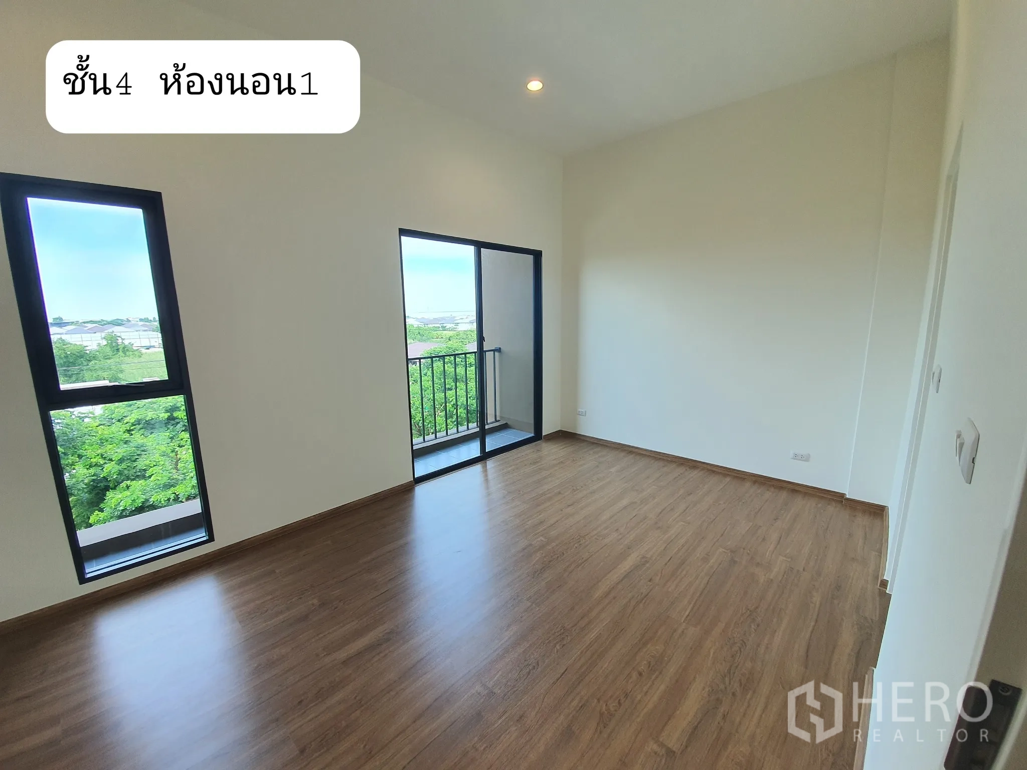 Home Office for rent or sale in Prawet, Bangkok - Master bedroom with a small balcony and tall window, wood floor and green neighborhood view.