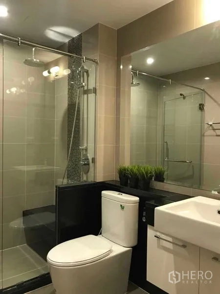 คอนโด ให้เช่าหรือขายในRatchathewi, Bangkok - ห้องน้ำสมัยใหม่พร้อมตู้กระจกอาบน้ำ กระจกบานใหญ่ และอ่างล้างหน้าสีขาว