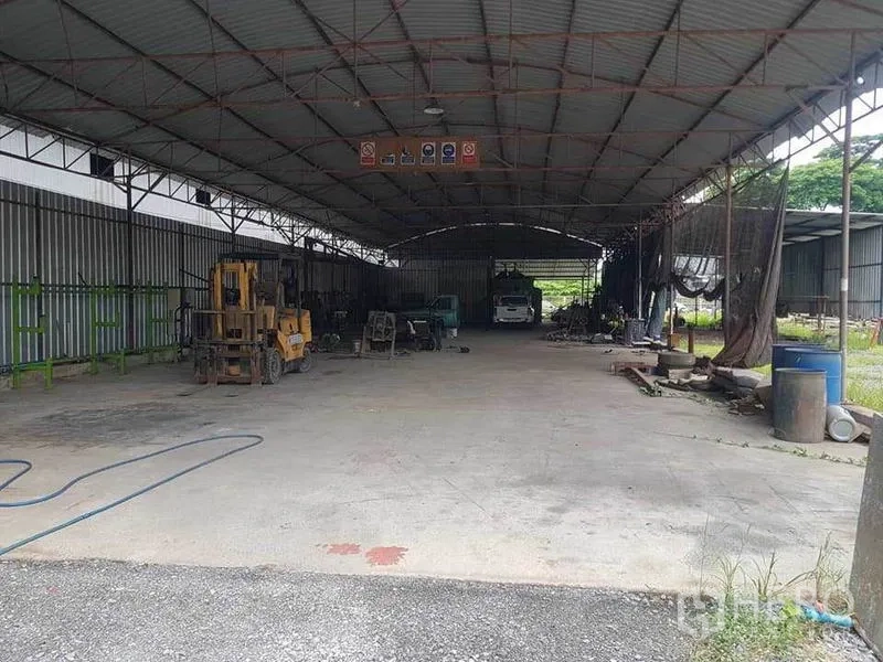 Warehouse for rent in Sai Noi, Nonthaburi - Spacious covered warehouse bay with steel roof, concrete floor and a forklift.