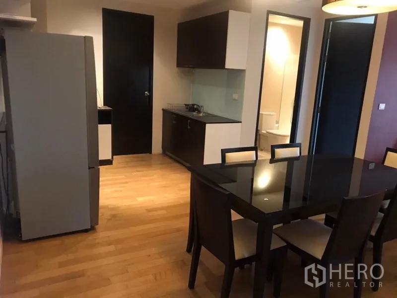 คอนโด ให้เช่าในWatthana, Bangkok - ครัวขนาดกะทัดรัดผนังกระจก ข้างโต๊ะอาหารหกที่นั่ง และมุมมองไปยังห้องน้ำ