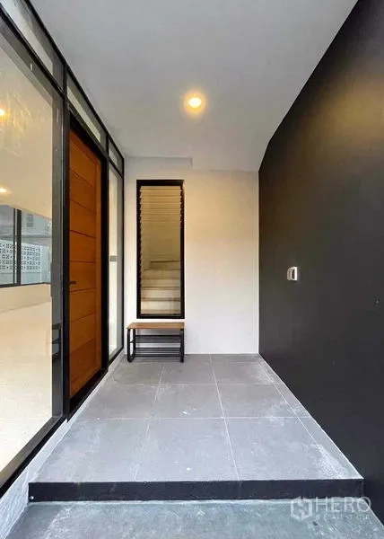 สำนักงานที่บ้าน ขายในLat Phrao, Bangkok - เฉลียงหน้าบ้านมีหลังคา พร้อมม้านั่ง ข้างประตูกระจกและประตูไม้